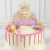 Topper na tort w kształcie bogato zdobionej karocy z koroną na szczycie i fioletową wstęgą z imieniem, personalizowany. Kolorystyka różowo-złota z lustrzanym efektem.