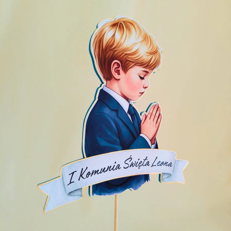 Elegancki, personalizowany topper na tort komunijny (efekt 3D). Ilustracja jasnowłosego chłopca (blondyna) w garniturze, na podkładzie ze złotego lustra i granatowego kartonu. Zawiera wypukłą szarfę z imieniem dziecka