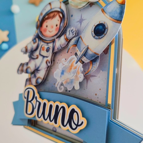 Kosmiczny, personalizowany topper na tort urodzinowy (spektakularny efekt 3D!). Wielowarstwowa kompozycja z uroczych astronautą, rakietą i planetami, oprawiona w niebiesko-złotą ramkę. Idealna dekoracja dla małego fana kosmosu!